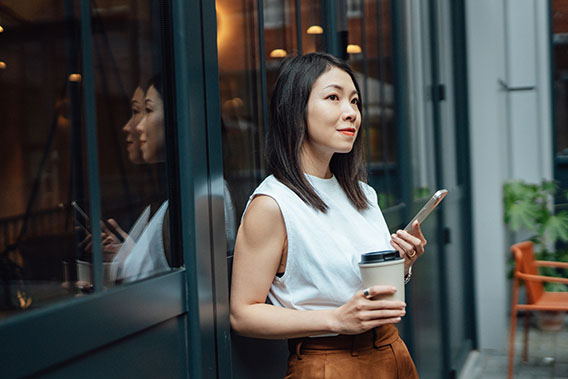 Young Asian woman taking a coffee break with smartphone.